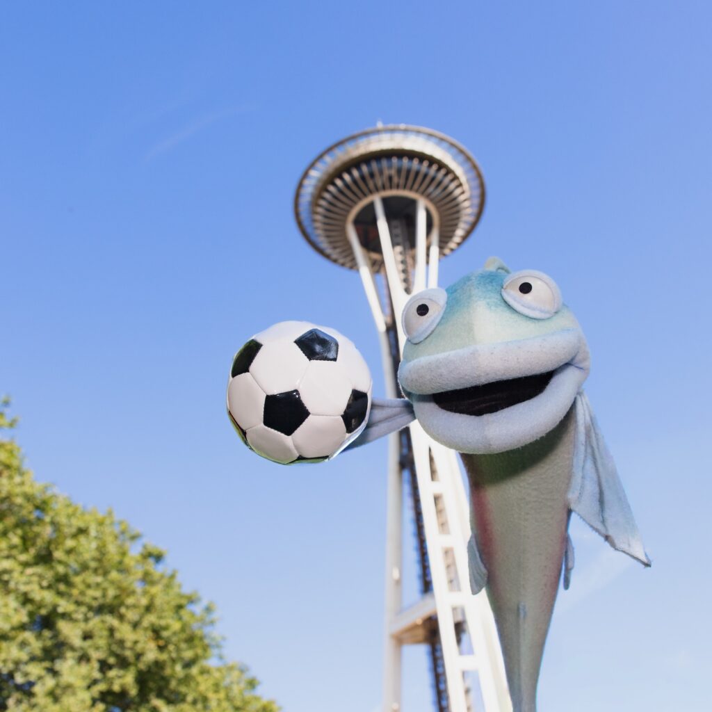 Sal appears perched on the space needle with a soccer ball.